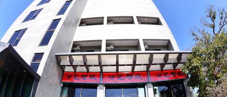 A modern building with a prominent entrance featuring large windows and a red sign with Chinese characters.