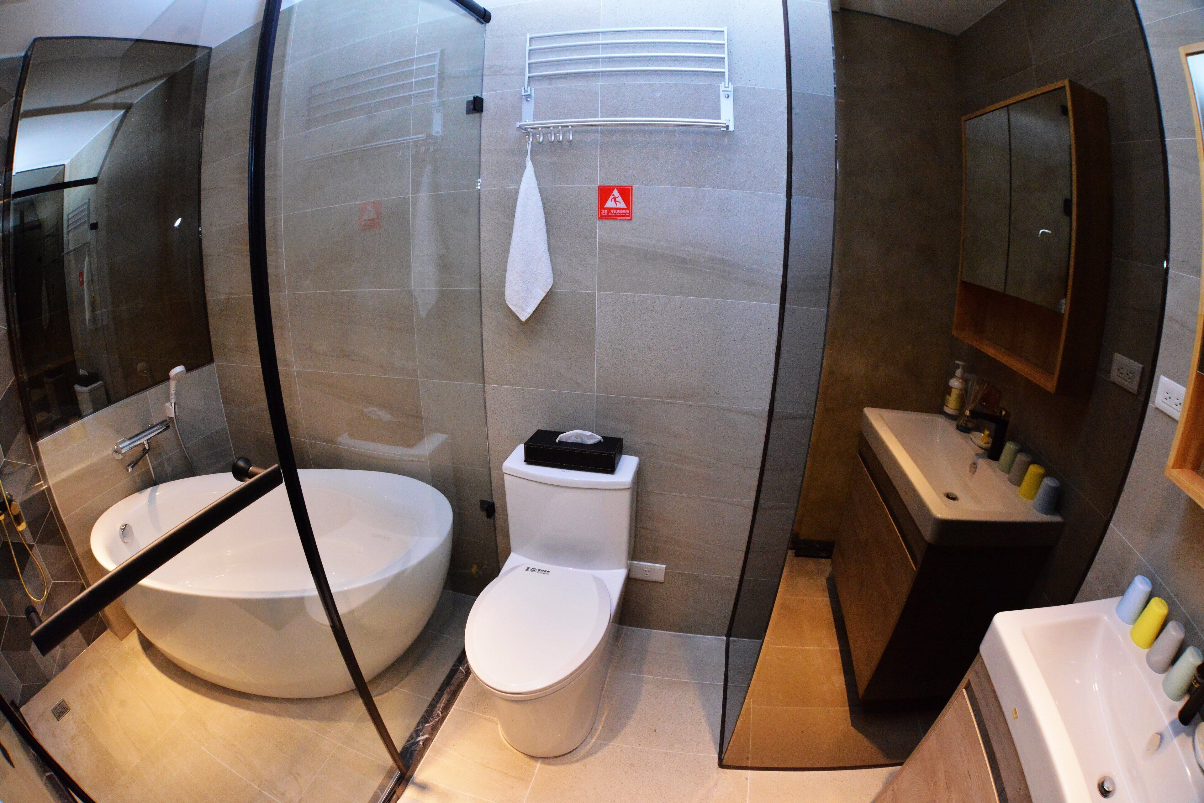 Ein modernes Badezimmer mit einer gläsernen Duschkabine, einer großzügigen Badewanne, einer Toilette und einem Waschbecken mit Pflegeprodukten.