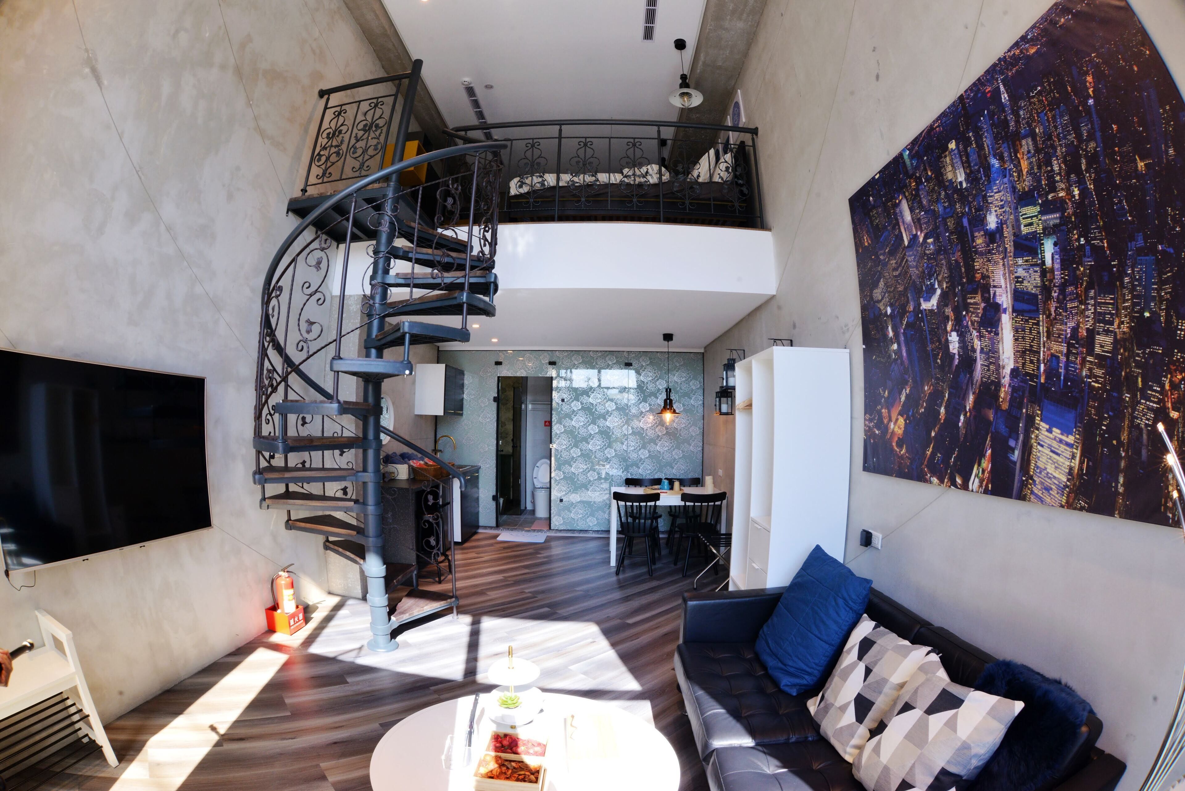 A spacious living area with a modern staircase, a dining area, and a large cityscape painting on the wall.