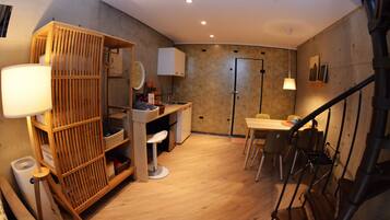 A compact kitchen with wooden cabinetry, a dining area with chairs, and a staircase.