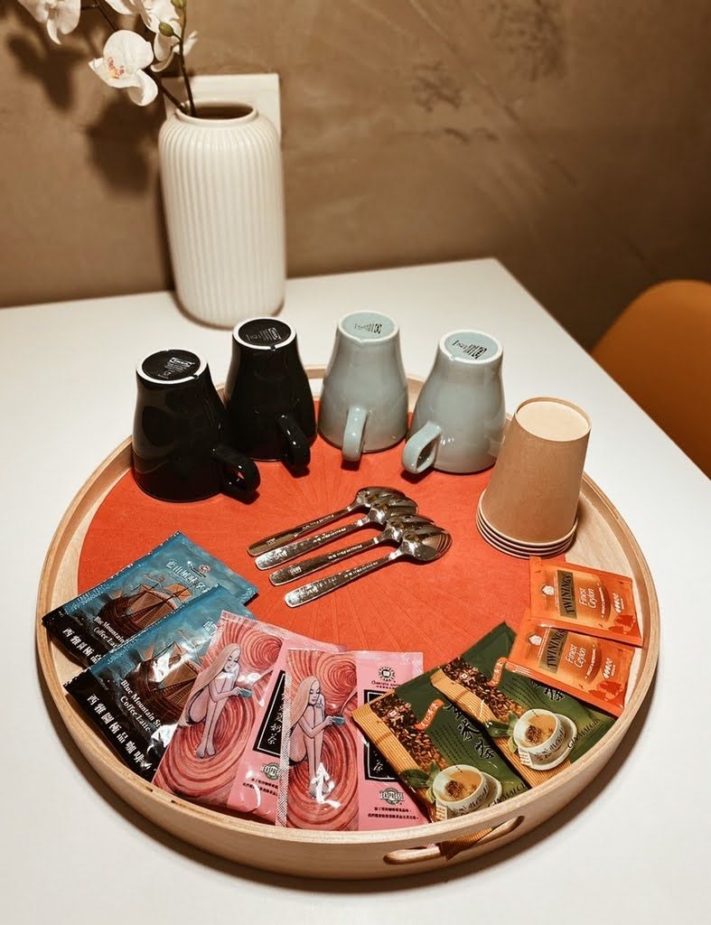 Een dienblad met diverse spullen, waaronder mokken, theepotten en portiegewijze snacks, wat doet denken aan een theeservies.