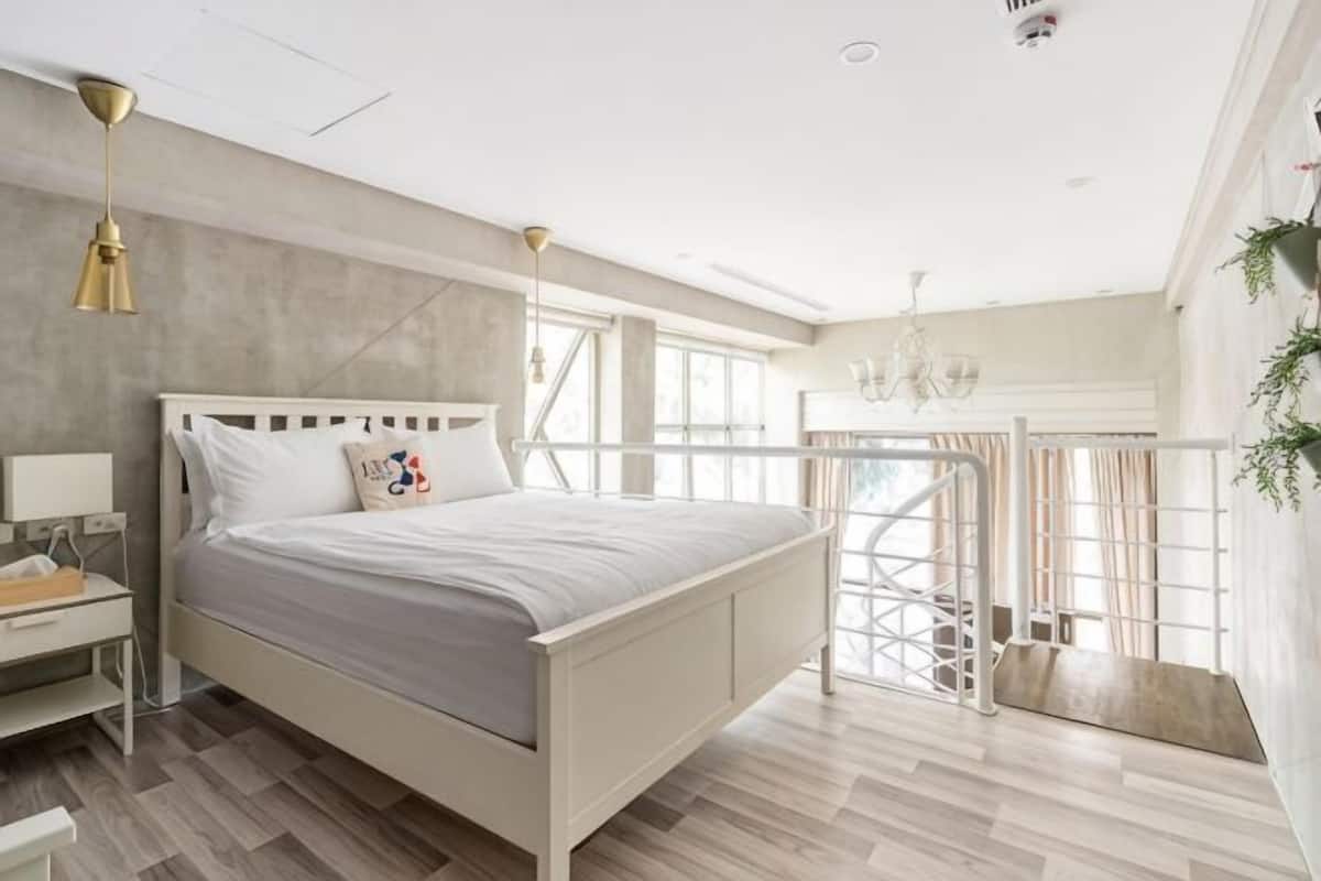 Une chambre Ă coucher avec un lit, un bureau, une chaise, une fenĂȘtre et un balcon.