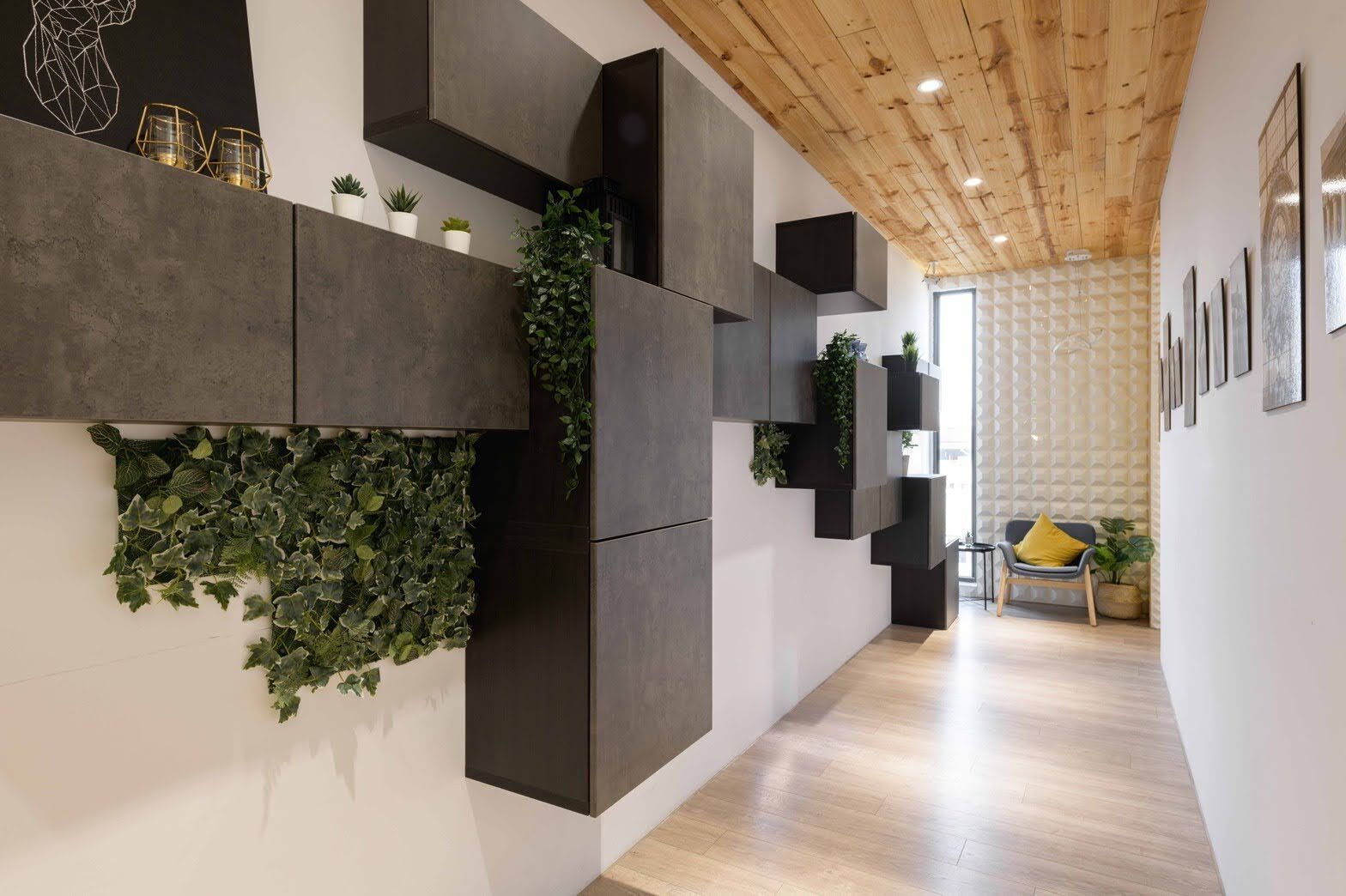 Un interior moderno con techo de madera, muebles oscuros y una pared cubierta de plantas verdes.