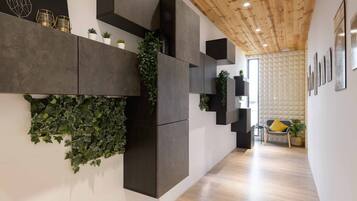 Un interior moderno con techo de madera, muebles oscuros y una pared cubierta de plantas verdes.