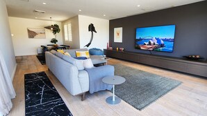 Un salon moderne avec un canapé gris, une table basse et un téléviseur à écran plat fixé au mur, qui diffuse une vue panoramique.