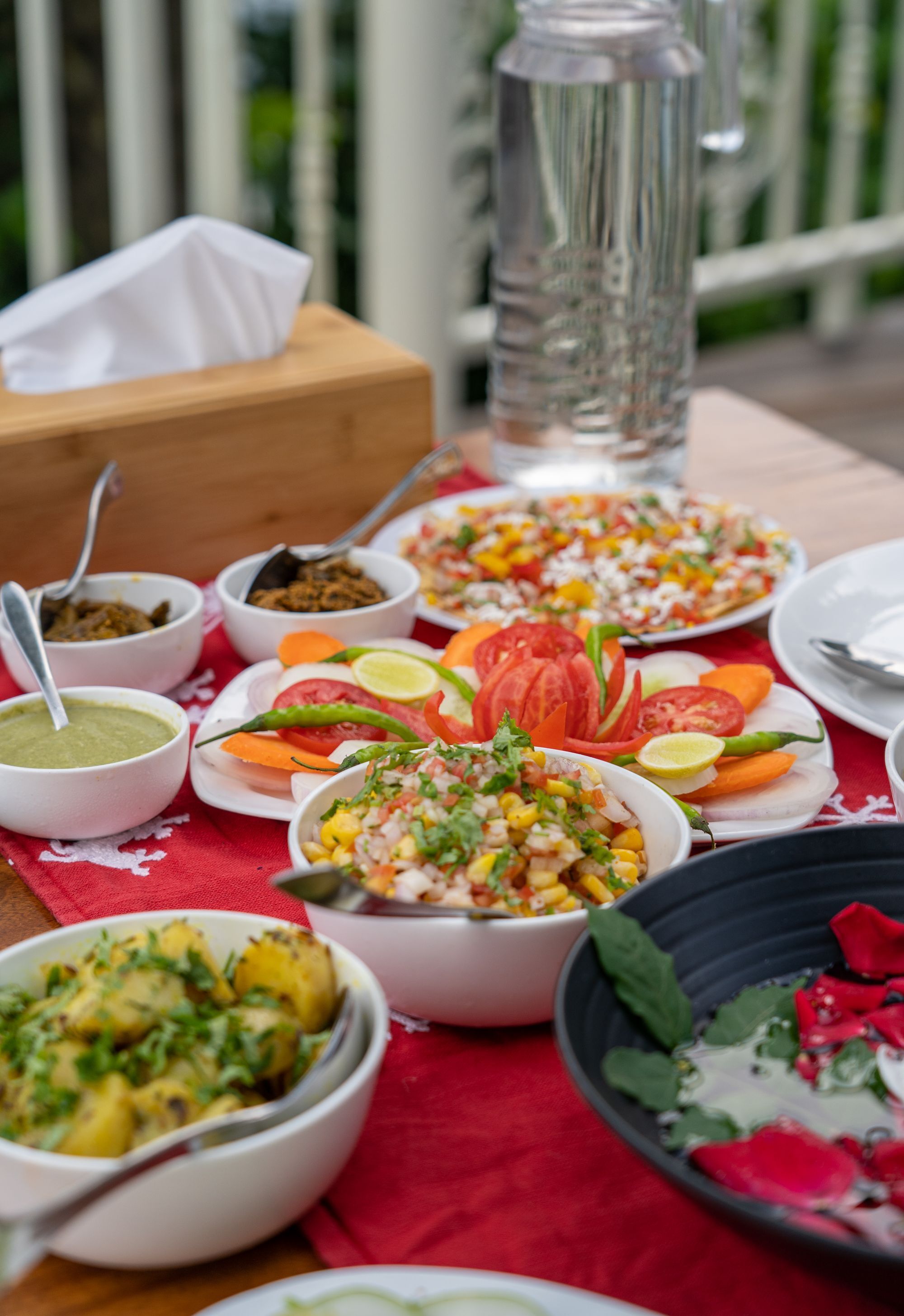 A table with various dishes and condiments, a water bottle, and a tissue box.