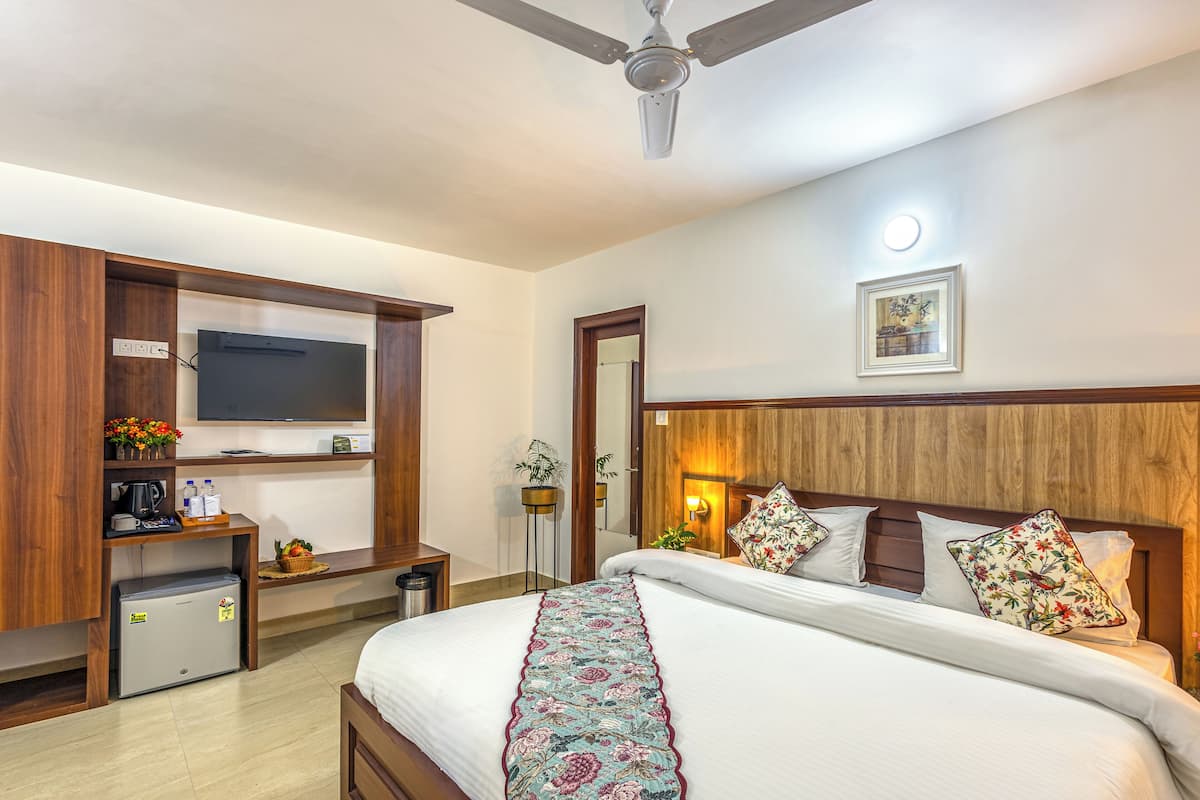 A hotel room with a bed, a TV, a desk, and a ceiling fan.