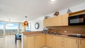 A modern kitchen with wooden cabinets, a black microwave, and a small oven.