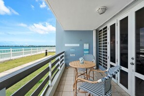 Un balcon avec vue sur la plage, une table avec des chaises et une pancarte sur laquelle on peut lire : « LA VIE SUR LA PLAGE ».