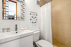 Une salle de bain avec un lavabo blanc, des toilettes et un rideau de douche.