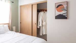 Un dormitorio con una cama, un armario y una obra de arte enmarcada en la pared.