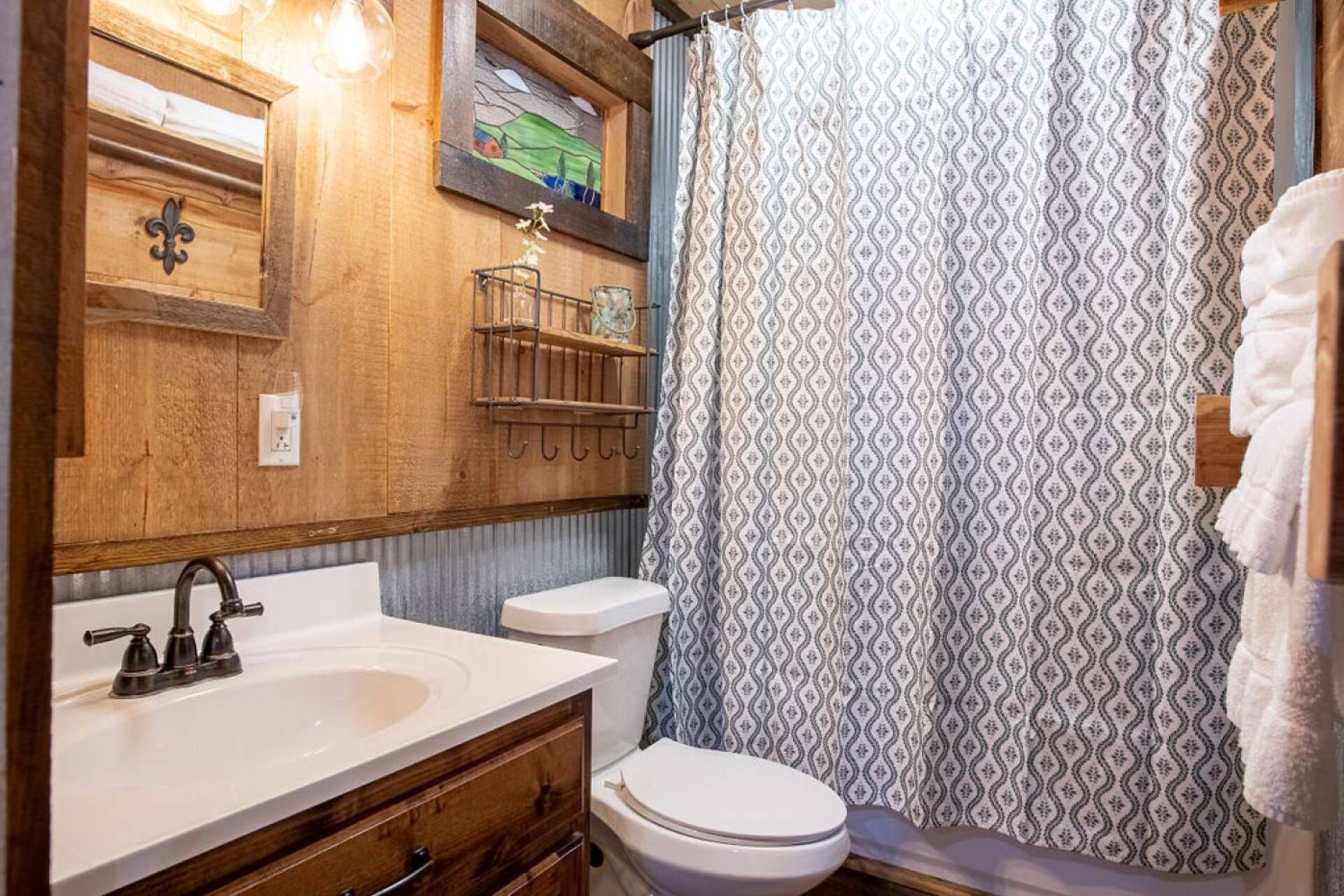 Un bagno con mobile bagno in legno, lavabo, WC e tenda per la doccia.