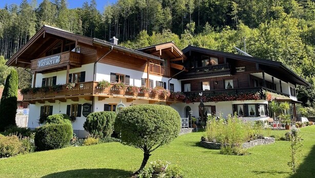 Un hotel de muntanya d'estil tradicional amb nombrosos balcons i un jardí ben cuidat.