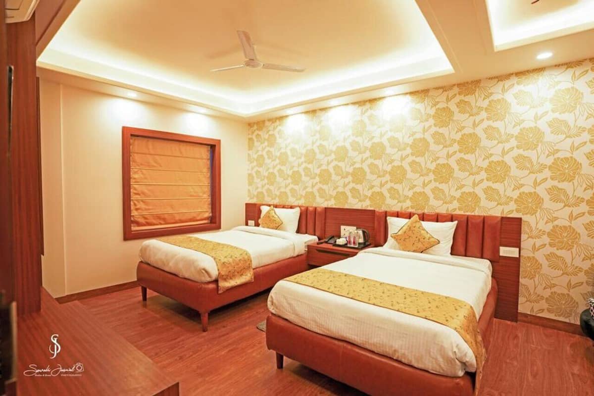A hotel room with two beds, a ceiling fan, and floral wallpaper.