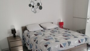 A bedroom with a bed, a nightstand, a red chair, and a wall decoration. - ENTRE MER ET FORET" vacation home (Le Tréport)