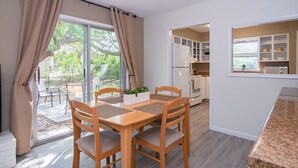 Un coin repas avec une table et des chaises en bois, une fenêtre avec des rideaux et une vue sur l’extérieur.