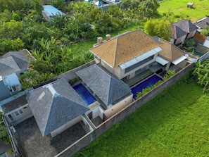 A modern house with a swimming pool, surrounded by lush greenery.