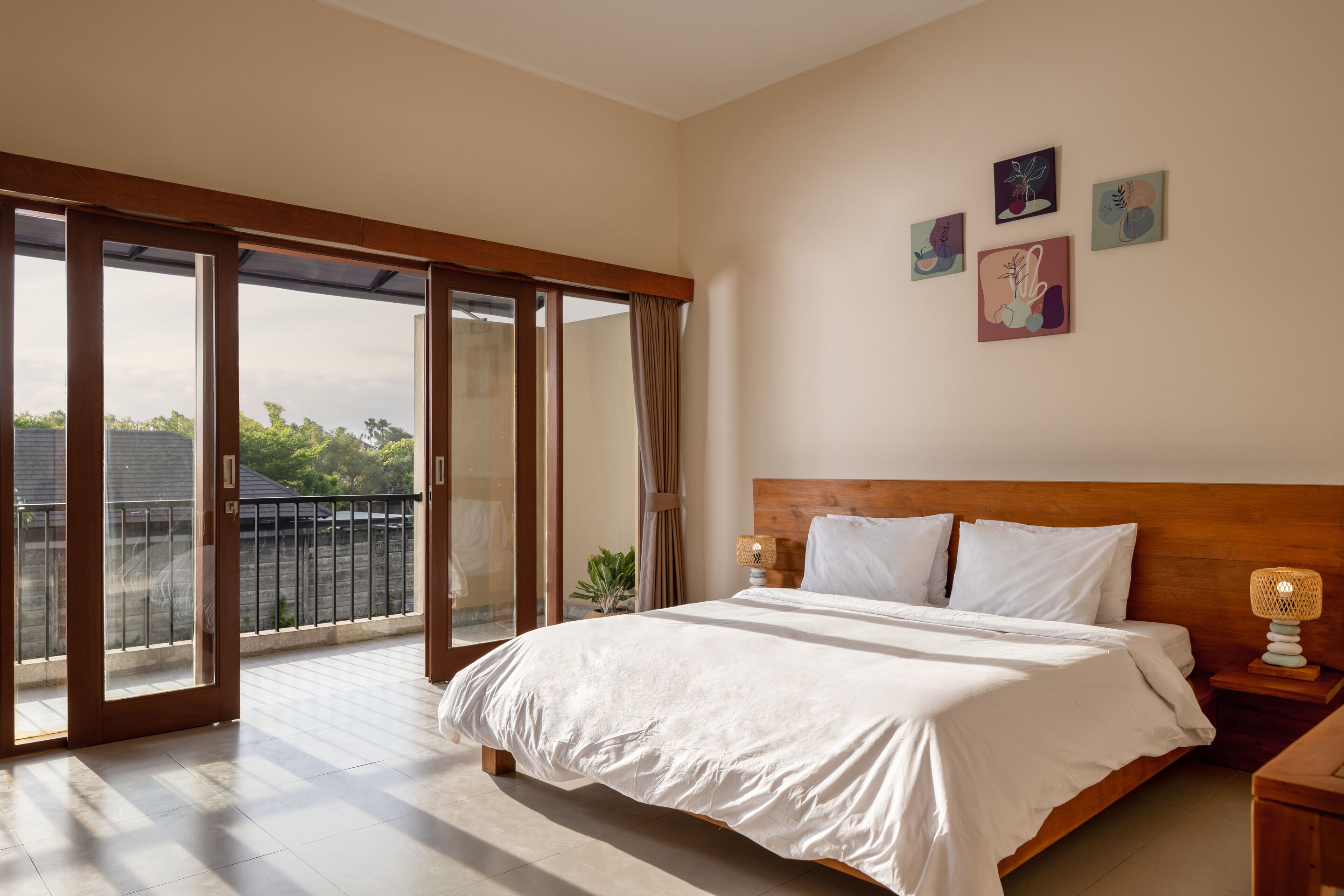 A bedroom with a large bed, a wooden headboard, and a balcony with glass doors.