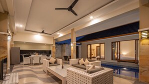Un hall d’hôtel moderne avec une piscine, un espace salon et une cuisine visible au fond.