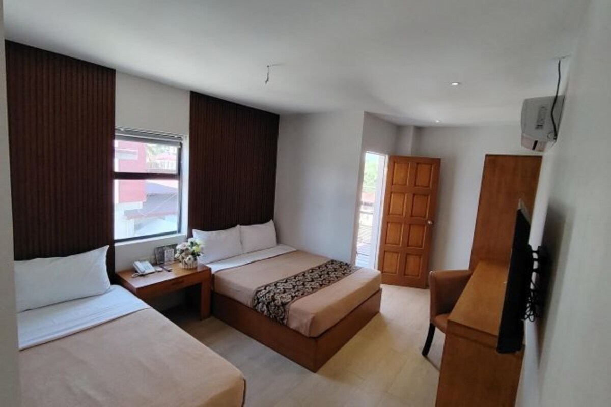 Habitación de hotel con dos camas, un escritorio, una silla, un armario y una ventana con cortinas.