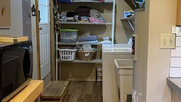 Une petite buanderie équipée d’étagères pour le linge, d’un lave-linge et d’un sèche-linge.