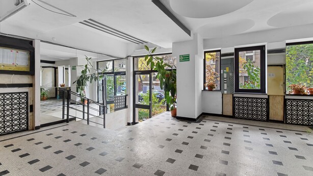 A spacious lobby with a tiled floor, a staircase, and potted plants. - Small & Chic Studio (Bucharest)