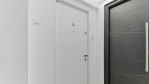 A white door with the number 20, a black door with a handle, and a small window on the white door. - Small & Chic Studio (Bucharest)