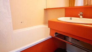 A bathroom with a white bathtub, an orange sink, and a wooden cabinet above the mirror. - Val Thorens - Cozy apartment for 4, ski-in/ski-out, elevator (Val Thorens)