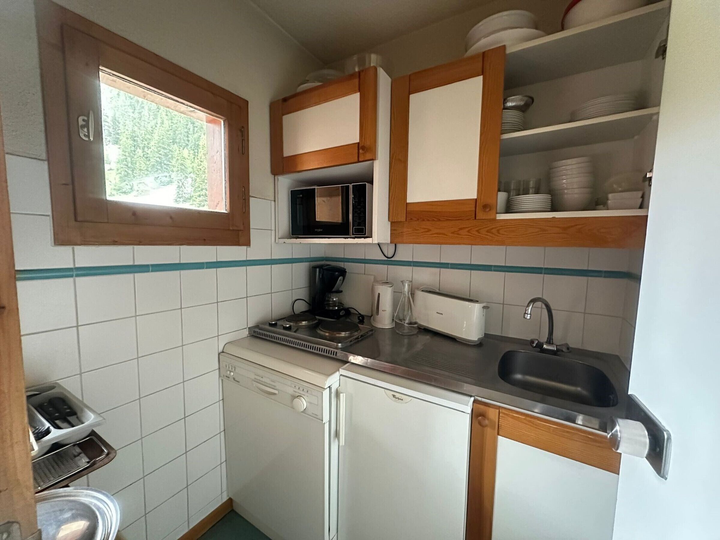 Kompakti keittiö, jossa on mikroaaltouuni, leivänpaahdin, pesuallas ja astianpesukone.