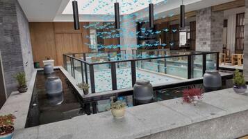 A modern interior with a glass railing, potted plants, and hanging lights.