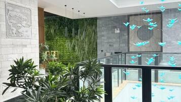 A modern interior with a glass railing, green wall, and hanging light fixtures.