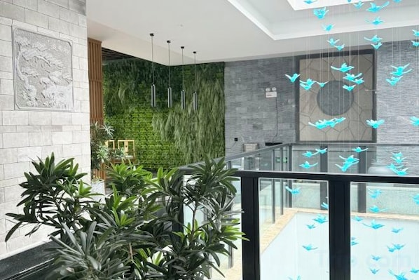 A modern interior with a glass railing, green wall, and hanging light fixtures.