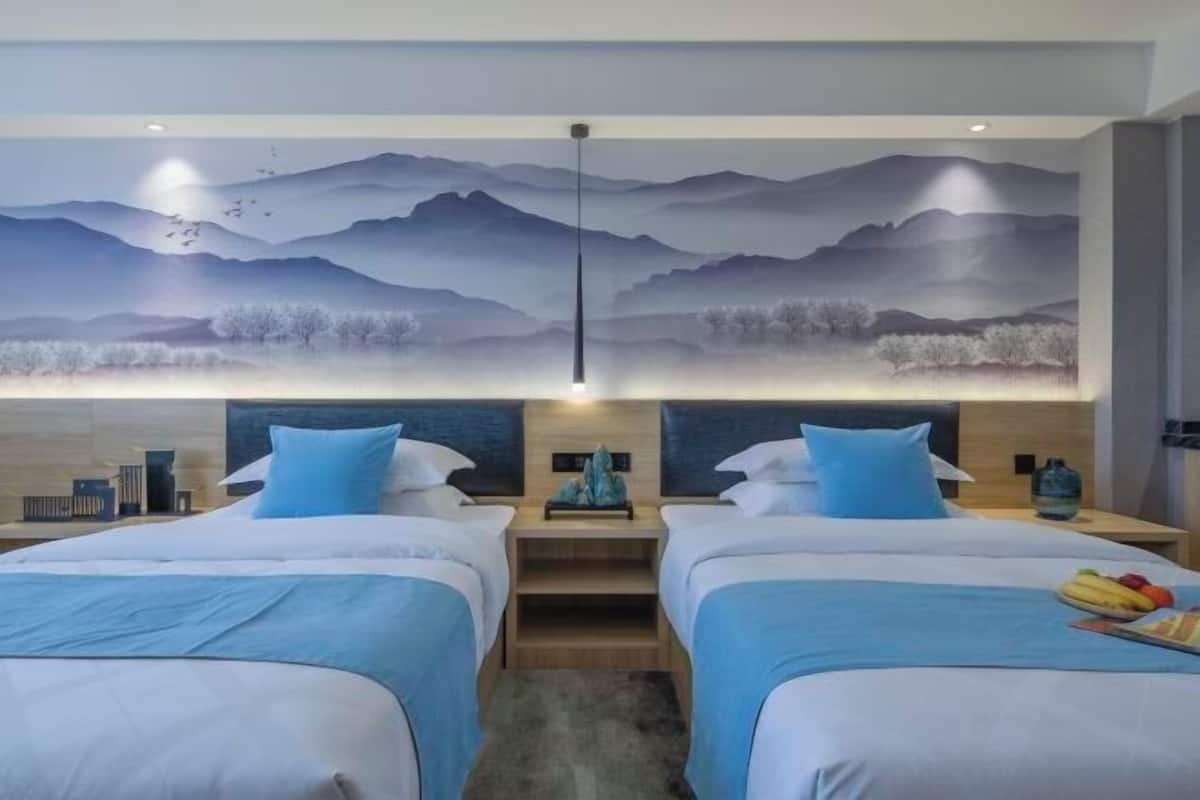 A hotel room with two beds, a large wall mural of mountains, and a modern design.