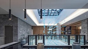 A modern interior with a glass railing, a skylight, and hanging paper birds. - Manyuegu Holiday Hotel (Xiangyun)