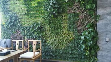 A wall with a vertical garden, wooden chairs, and a table.