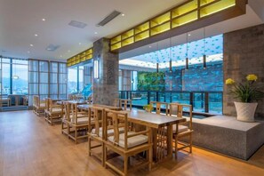 A modern dining area with wooden furniture and large windows offering a city view.