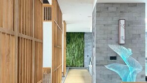 A corridor with wooden partitions, a green wall, and a modern sculpture. - Manyuegu Holiday Hotel (Xiangyun)
