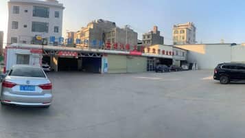 A parking lot with a building entrance, a car, and a few other vehicles.