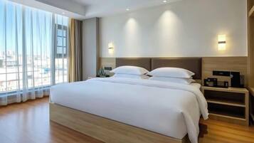 A modern hotel room with a large bed, bedside tables, and a city view.