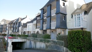 Una fila di edifici moderni a più piani, con balconi, un’area parcheggio coperta e un ponte pedonale.