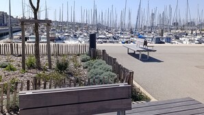 Un porto turistico con numerose imbarcazioni ormeggiate, una panchina di legno e un cielo sereno.