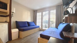 Una camera d'albergo compatta con un letto, una piccola scrivania, un divano e un angolo cottura.