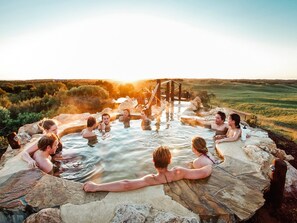 A group of people in a hot spring surrounded by natural landscape.