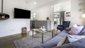 Ein modernes Wohnzimmer mit einer Couch, einem Couchtisch und einem an der Wand befestigten Flachbildfernseher.