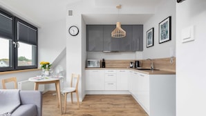 Una cocina moderna con armarios blancos, encimera de madera y una lámpara colgante.