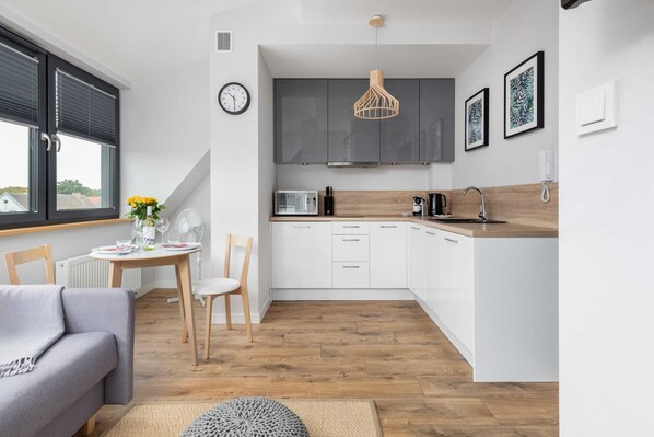 Una cocina moderna con armarios blancos, encimera de madera y una lámpara colgante.