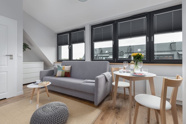 A modern living and dining area with large windows, a cozy sofa, and a stylish table setting.