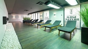 Un área de espera moderna con sillones reclinables, un camino de grava y un letrero que indica un centro de spa o bienestar.