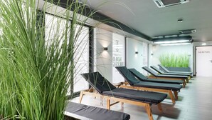 Un cuarto de spa con varias camillas de masaje, una planta de interior grande y una pared con texto.