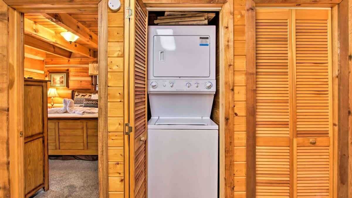 Una cabaña de madera compacta con lavadora y secadora integradas, una kitchenette pequeña y un rincón de descanso acogedor.